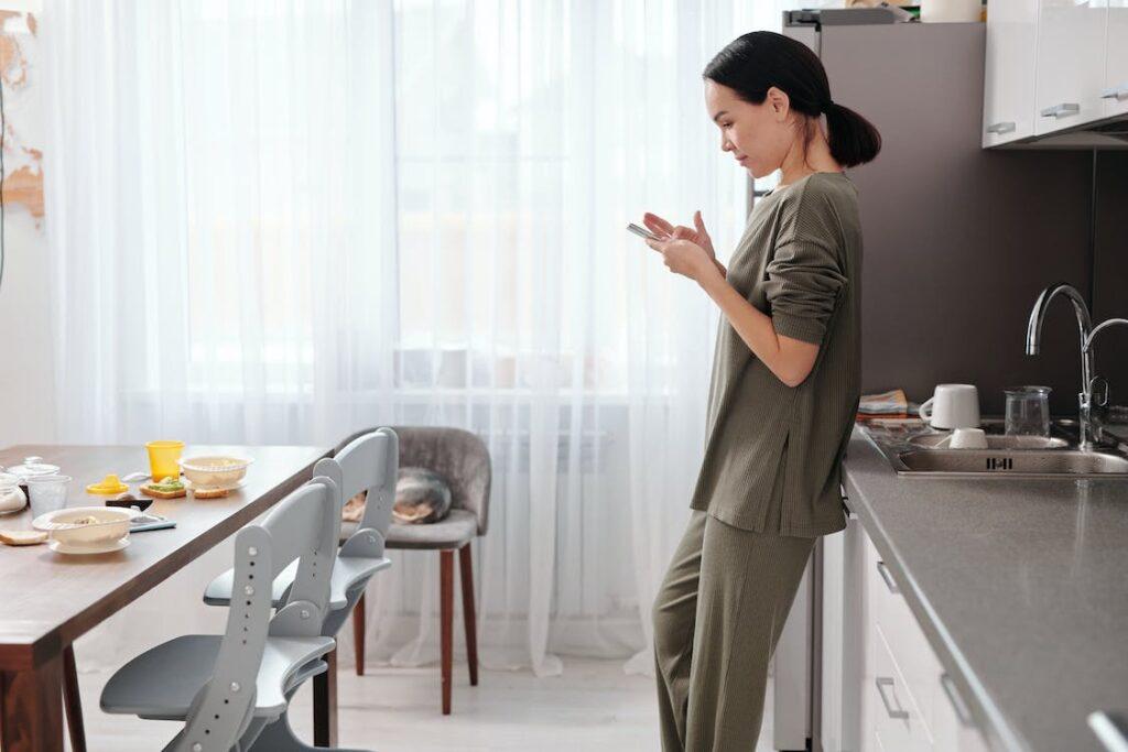 Frau mit Handy in der Küche